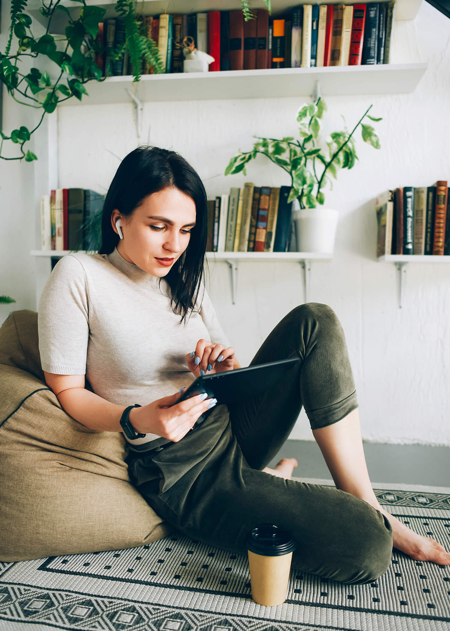 Image of a woman sitting in a beanbag chair while using a tablet. This image illustrates what online therapy in California with an online DBT therapist in California may look like for someone in a DBT program. | 90266 | 90505
