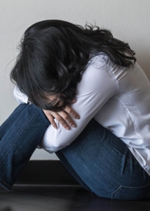 Image of a woman curled up on the floor hugging her knees to her chest. This image represents someone who may be struggling with managing anger in Los Angeles, CA. Those with anger issues in Los Angeles, CA can get help in DBT therapy. | 90254 | 90266 | 90505