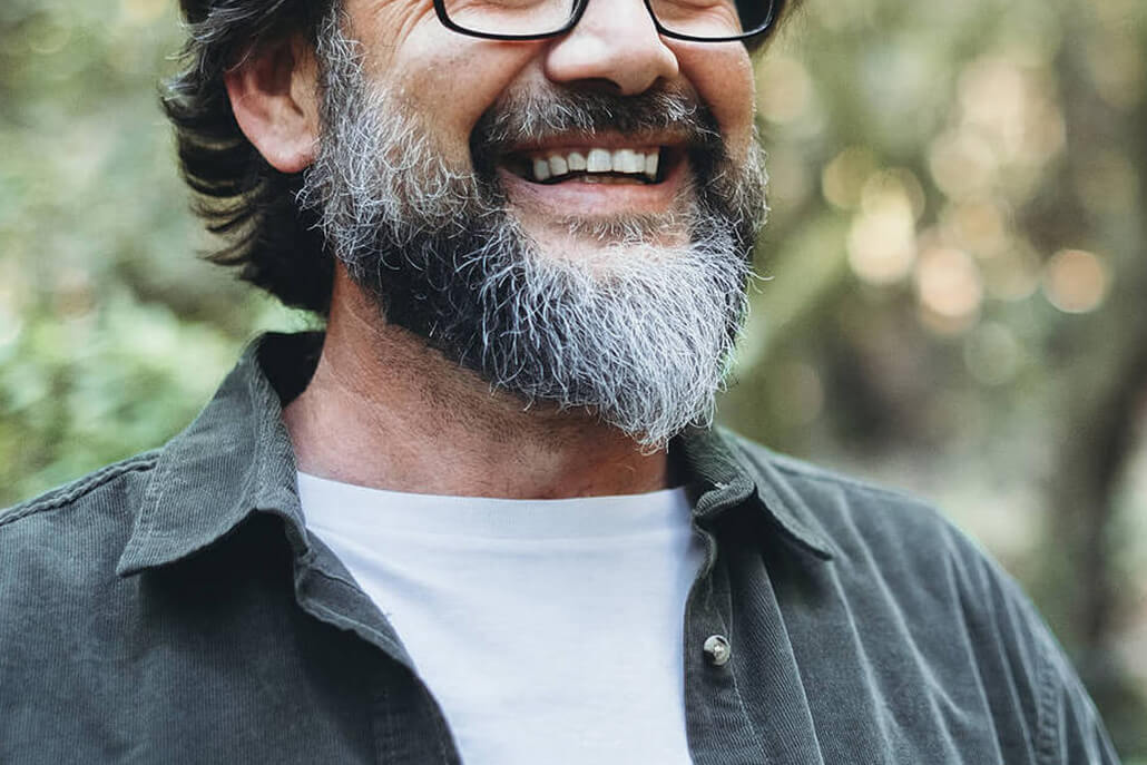Image of an older bearded man wearing glasses and smiling. If you struggle with depression, learn to cope with your symptoms in healthy ways with the help of EMDR therapy in Las Vegas, NV.