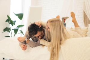 Image of a playful couple smiling while laying in bed. Discover how borderline personality disorder therapy in Las Vegas, NV can help you connect with others in healthy ways.