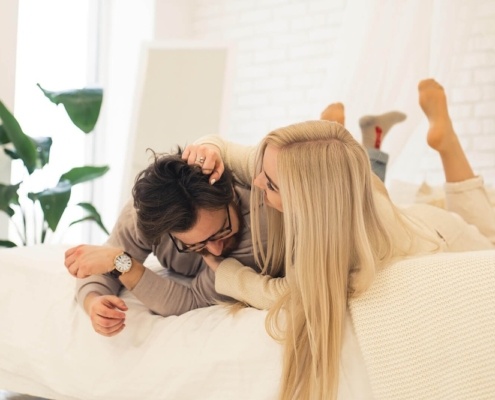 Image of a playful couple smiling while laying in bed. Discover how borderline personality disorder therapy in Las Vegas, NV can help you connect with others in healthy ways.