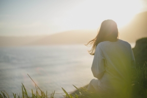 Image of a woman sitting on the top of a hill overlooking the ocean during sunrise. Discover how DBT and EMDR therapy in Las Vegas, NV can help you begin to cope with your trauma.