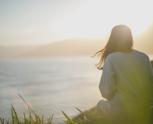 Image of a woman sitting on the top of a hill overlooking the ocean during sunrise. Discover how DBT and EMDR therapy in Las Vegas, NV can help you begin to cope with your trauma.