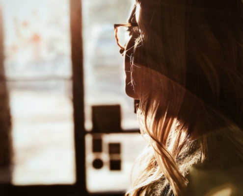 Image of a woman looking out a window with the sun shining on her face. Discover how EMDR therapy in Las Vegas, NV can help you cope with your depression symptoms.