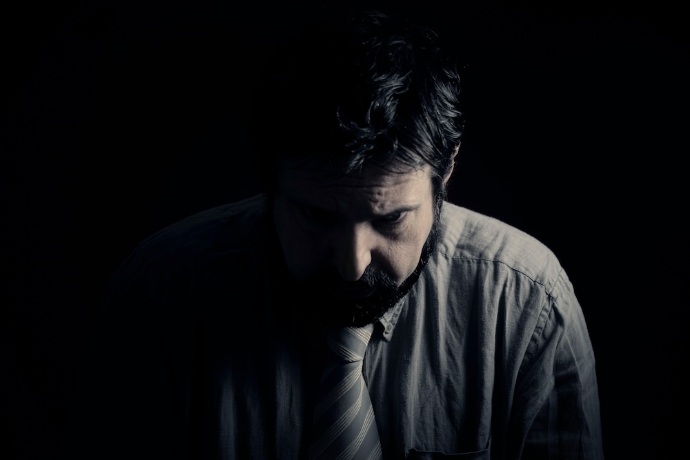 Image of a professional man looking down with a dark cast over his face. Learn to effectively manage your depression with DBT and EMDR therapy in Las Vegas, NV.