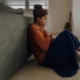 Image of a woman sitting on the floor leaning against a couch holding her hand to her chest. Discover how you can fight your anxiety symptoms with the help of EMDR therapy in Las Vegas, NV.