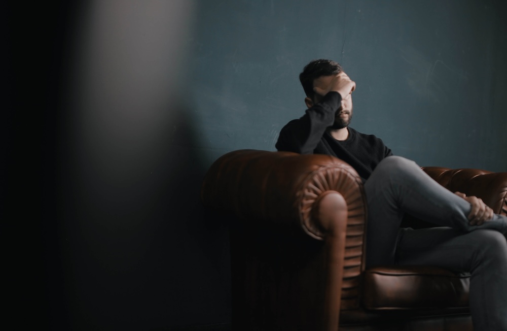 Image of a man sitting on a leather couch in therapy resting his hand on his forehead. Uncover the root of your trauma and start coping with the help of EMDR therapy in Las Vegas, NV.