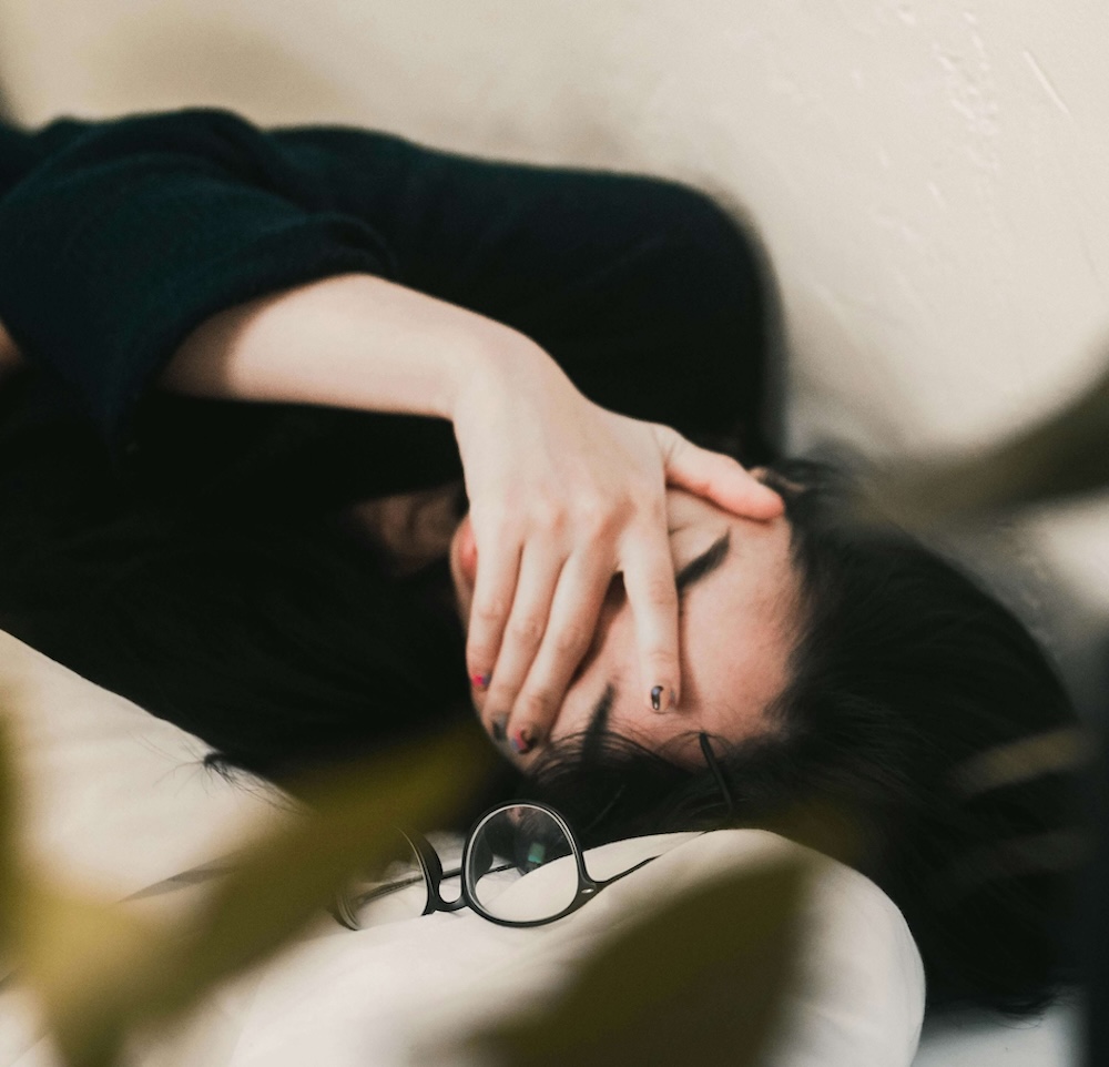 Image of a tired woman laying down with her hand, covering her face. Discover how EMDR therapy in Las Vegas, NV can help you cope with the nightmares, you face due to past trauma.