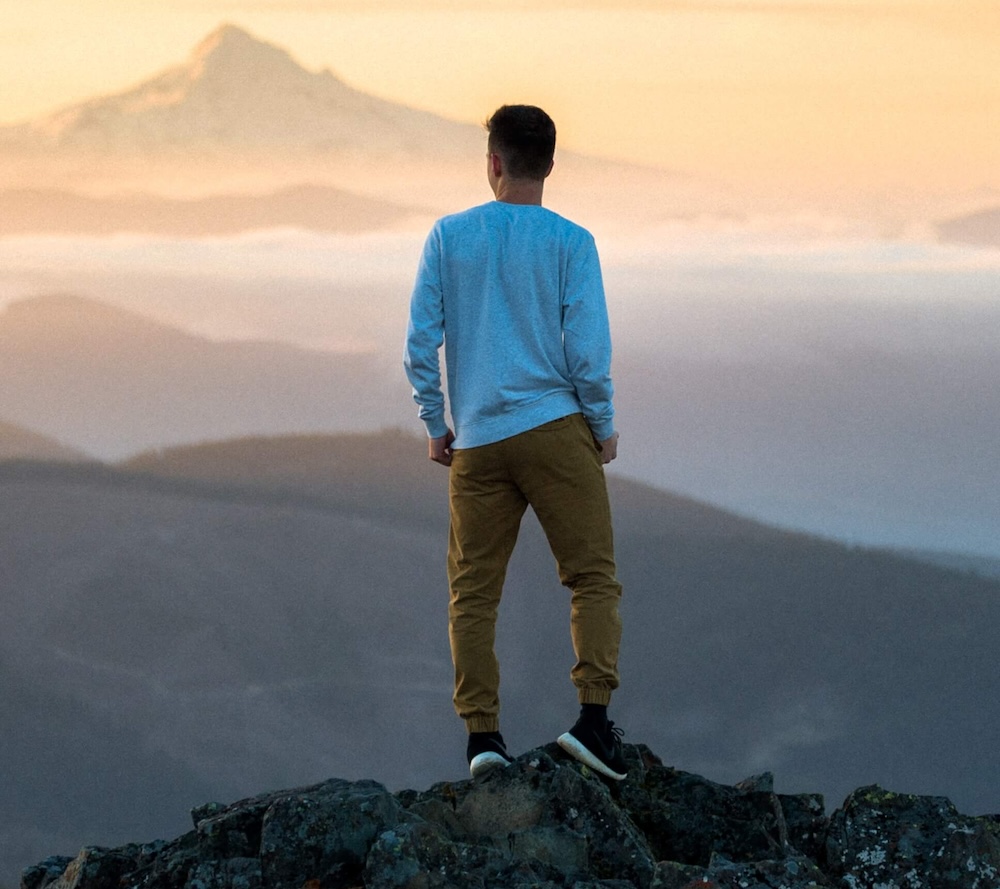 Image of a man standing on top of a mountain overlooking the valley below during sunrise. Understand your personality disorder and how you can manage it with the help of an EMDR therapist in Las Vegas, NV.