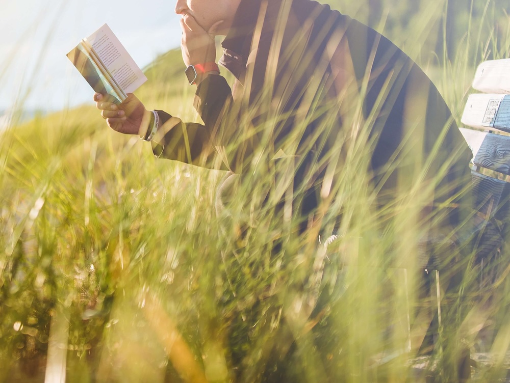 Image of a man sitting on a bench on a sunny day reading a book. Begin learning more about your attachment style and how it affects your with EMDR therapy in Las Vegas, NV.