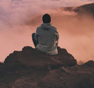 Image of a man sitting on a rock looking over the clouds. Learn how EMDR therapy in Las Vegas, NV can help you cope with trauma.