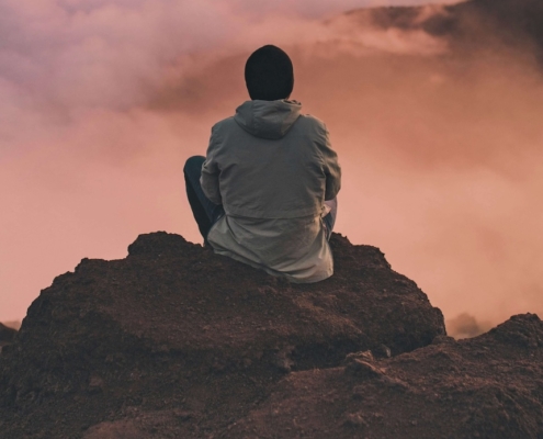 Image of a man sitting on a rock looking over the clouds. Learn how EMDR therapy in Las Vegas, NV can help you cope with trauma.