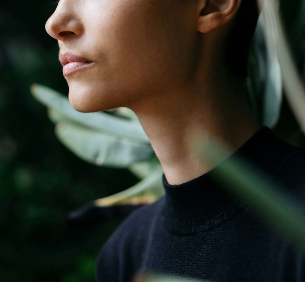 Image of a calm young woman wearing a black shirt surrounded by plants. Learn effective ways to manage your stress with mindfulness in Las Vegas, NV.