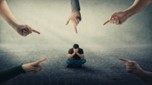 A group of hands point surrounding a person sitting on the ground and covering their face. Learn how an EMDR therapist in Las Vegas, NV can offer support with addressing social anxiety. Learn more about EMDR in Las Vegas, NV by searching for emdr therapy for anxiety in Las Vegas, NV
