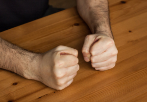 A close up of balled fists on a table. Learn how a DBT therapist in Torrance, CA can offer support by searching for online DBT therapy and other forms of support. Search for DBT therapy in Las Vegas to learn more.