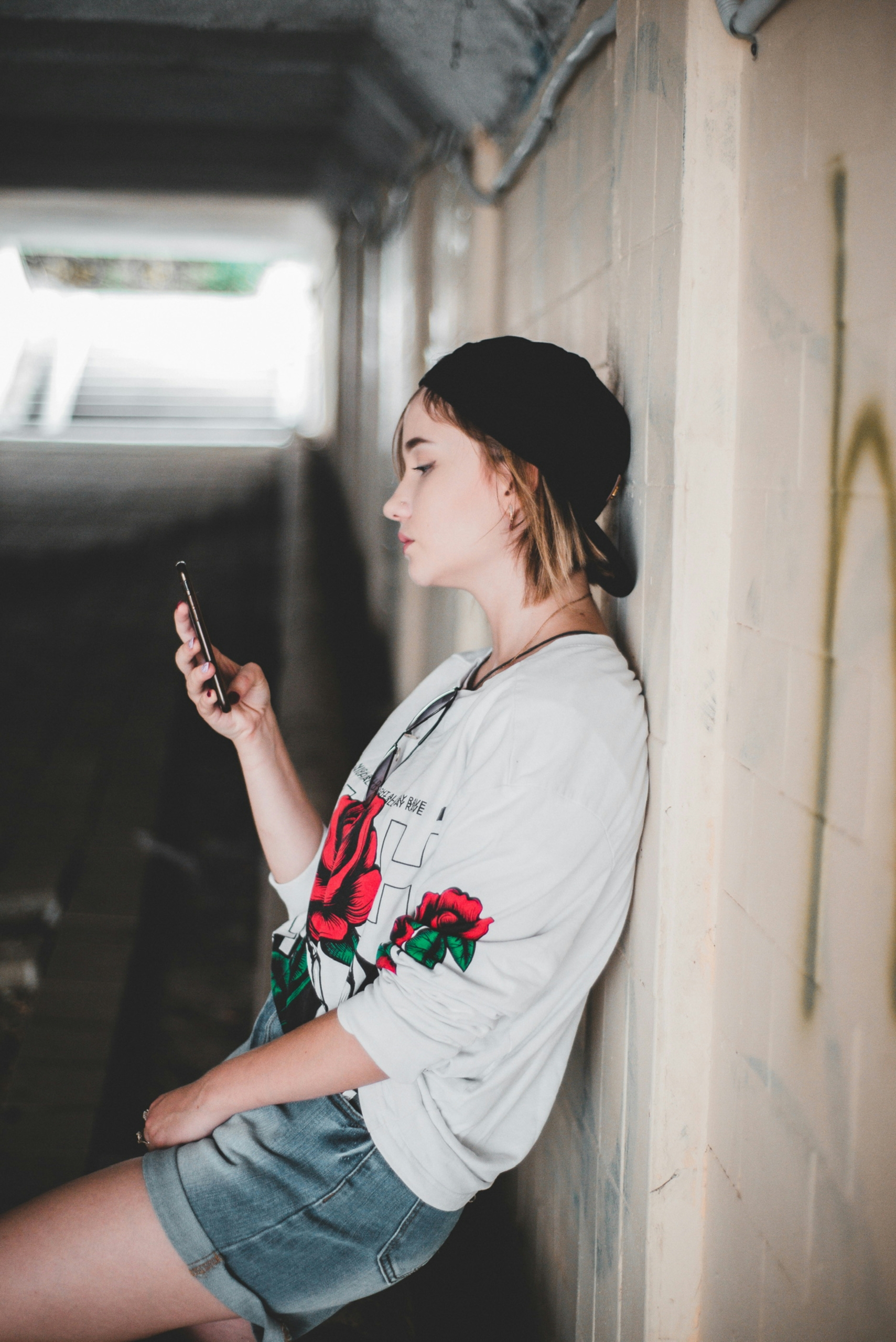 Person pausing and looking at phone in a quiet moment, representing DBT phone coaching support during urges