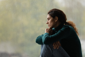 Woman sitting by a window, deep in thought, symbolizing emotional reflection and readiness for EMDR therapy
