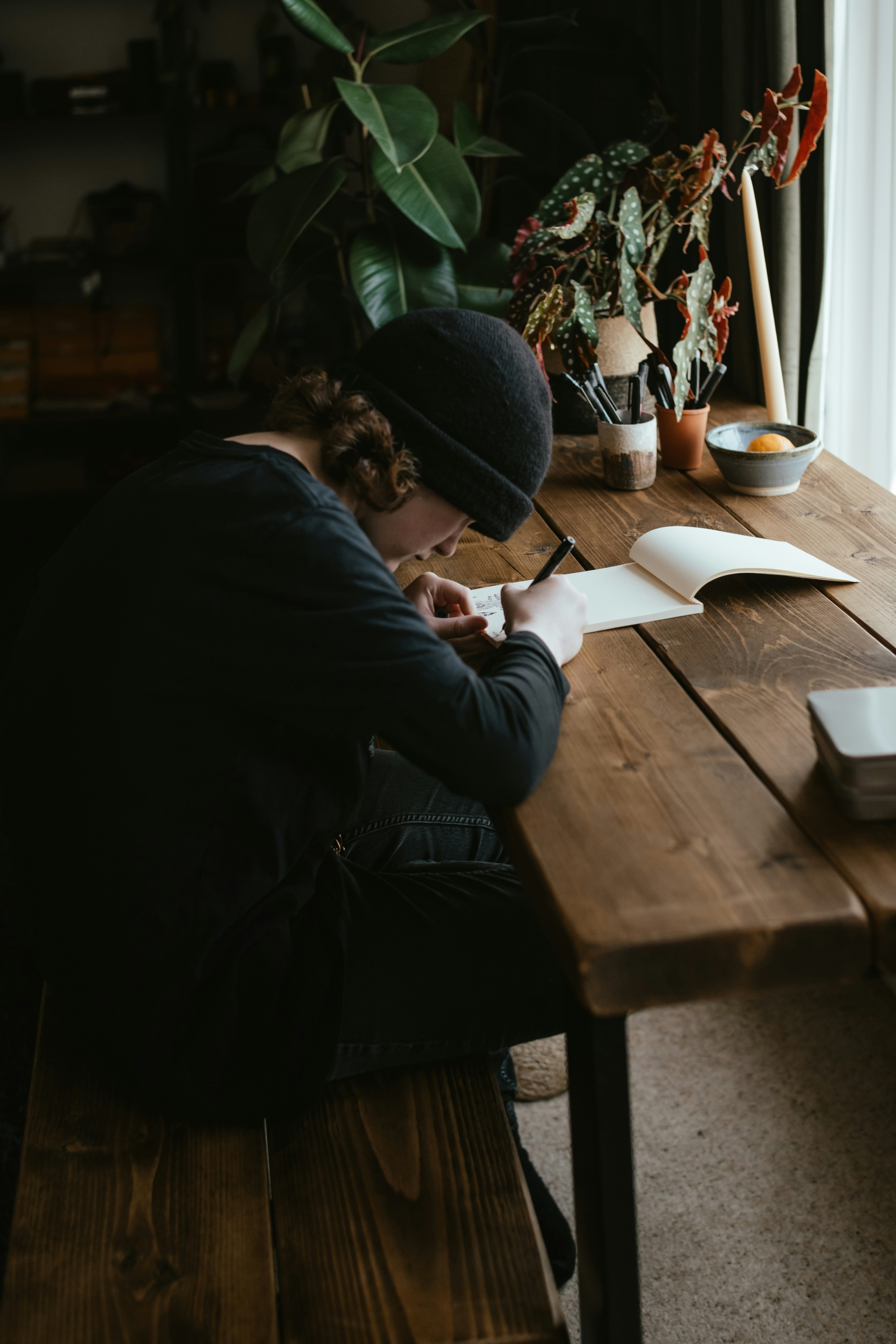 Young woman sitting at a desk, writing in a notebook with focus and concentration