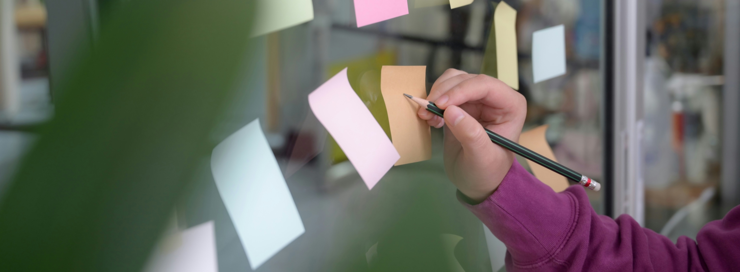 Person surrounded by open notebooks, reading and writing at a desk with a cup of coffee nearby