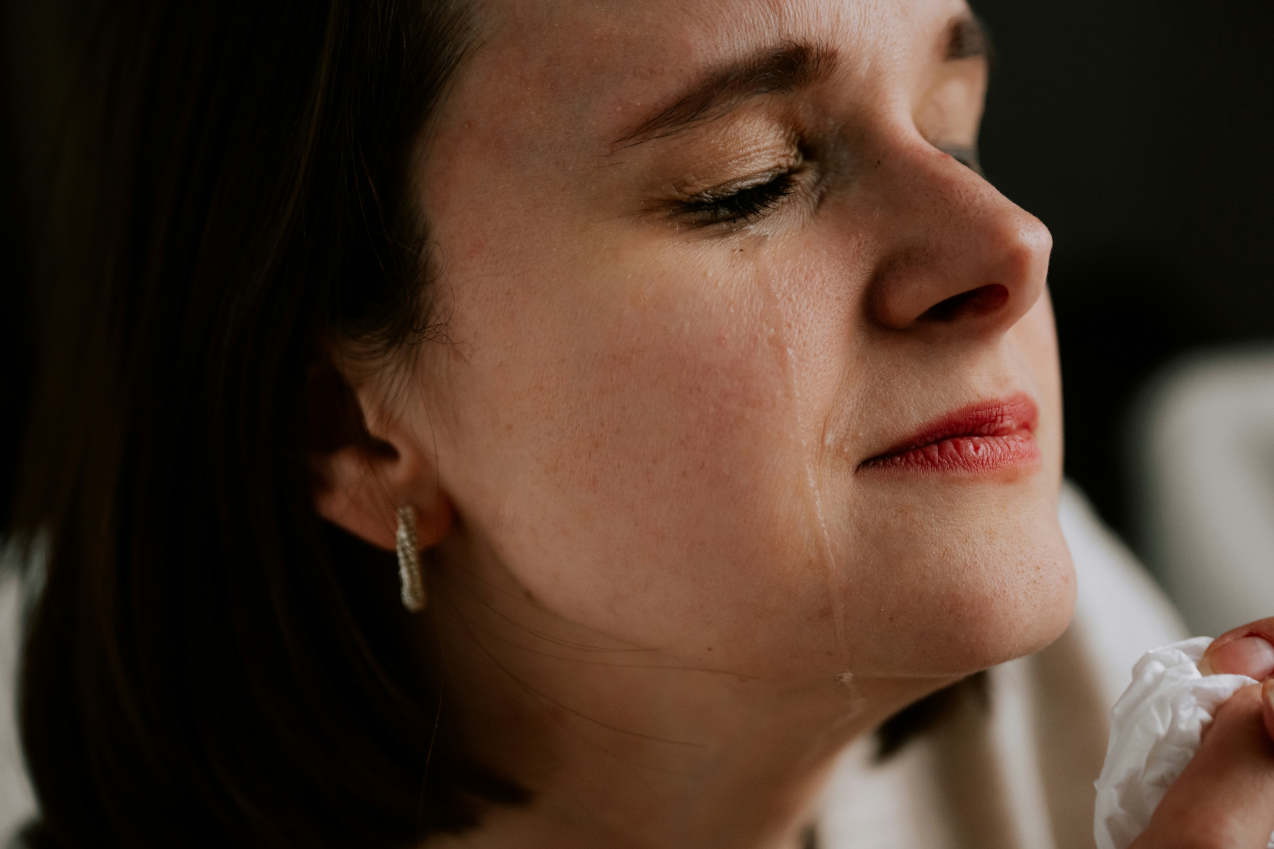 A close-up of a woman crying with a tissue in her hand, showing the emotional cost of ADHD and emotion dysregulation.