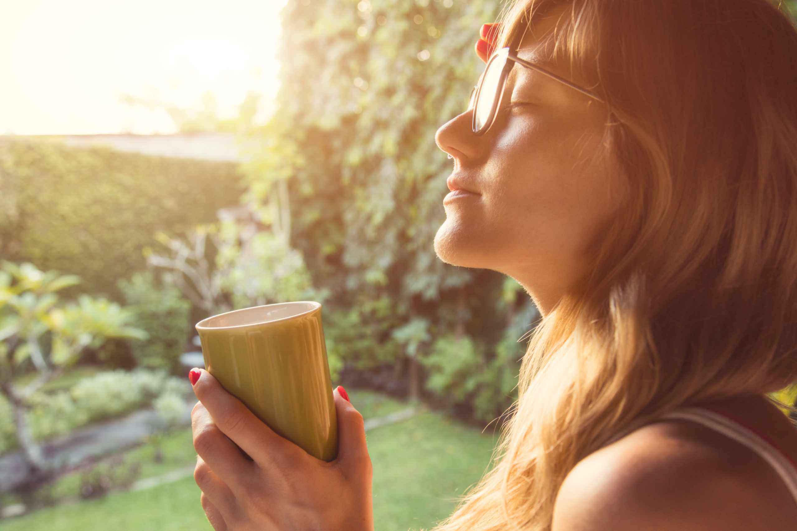 Woman enjoying a quiet moment with coffee in the morning sun — an example of DBT’s Accumulating Positives skill through short-term daily deposits.
