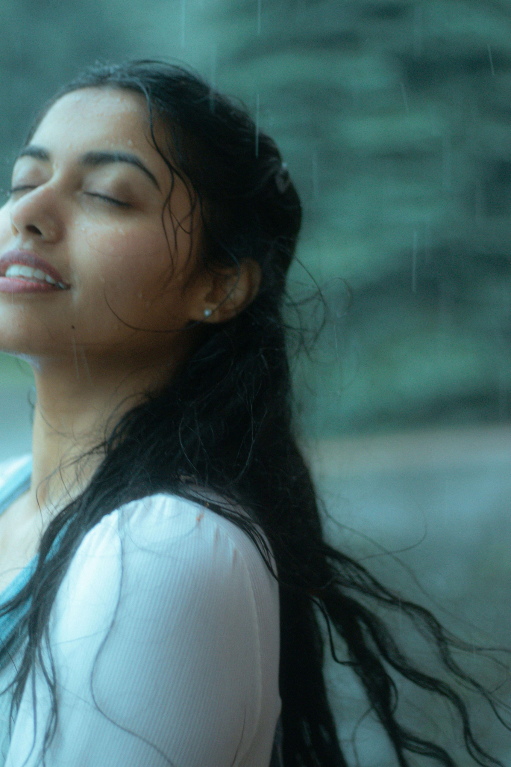 A woman stands in the rain with her eyes closed, embracing the present moment. Practicing mindfulness helps manage each current emotion without resistance. An online DBT therapist in Torrance, CA, can support emotional regulation and acceptance.