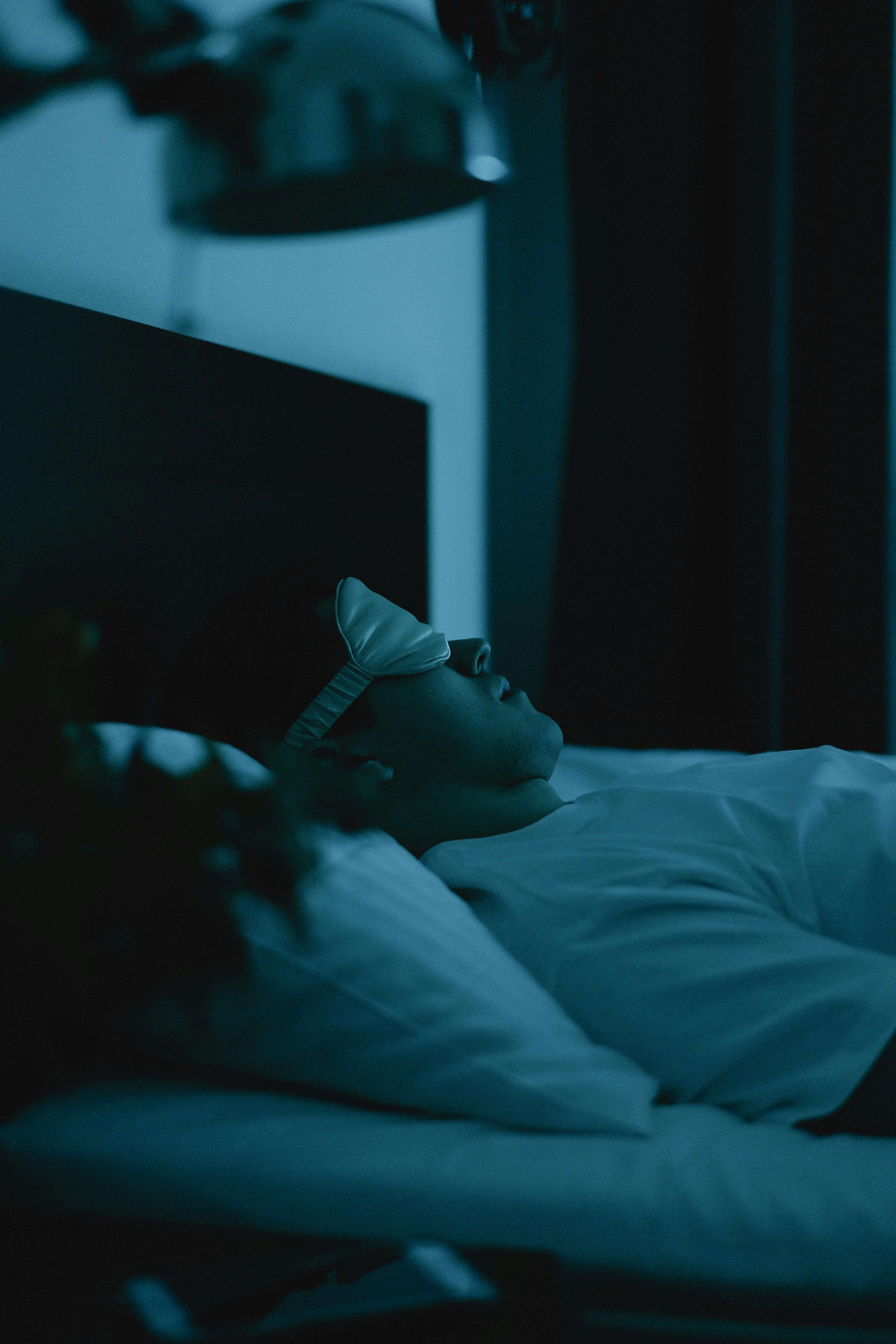 A man rests in bed wearing a sleep mask, representing the intentional practices that strengthen sleep hygiene. Are you considering whether DBT skills in Las Vegas, NV, might help you settle your mind before bed? Evening routines can shift restless nights into restorative sleep.
