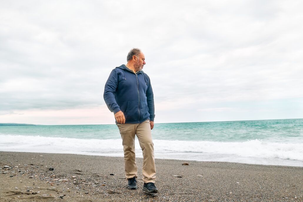 Man walking along the shore, looking out toward the ocean